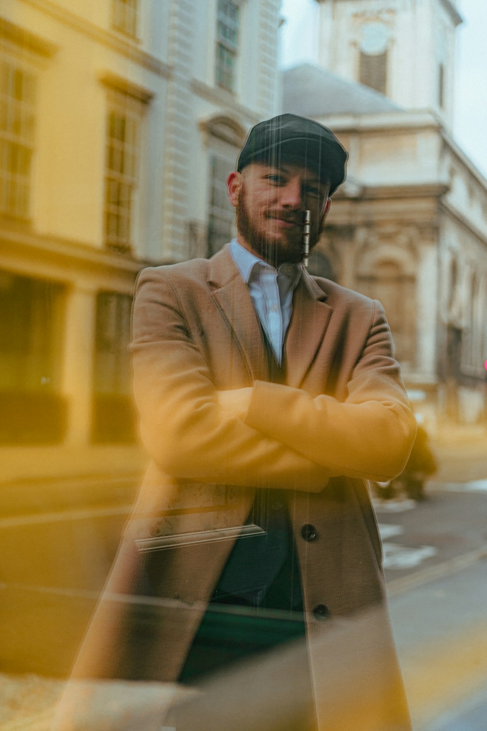 man in brown coat standing near yellow building during daytime