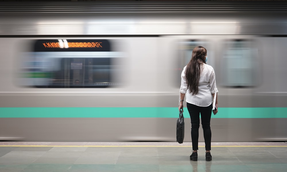 woman in white jacket standing beside train