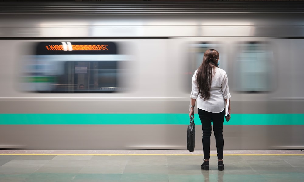 woman in white jacket standing beside train