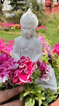 Statue of Shakira in Barranquilla surrounded by colorful flowers and blue sky.