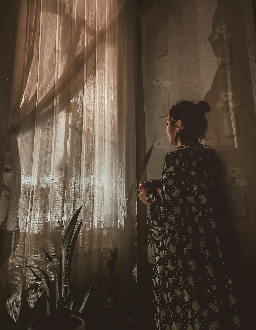 woman in black and white floral dress standing near white floral curtain