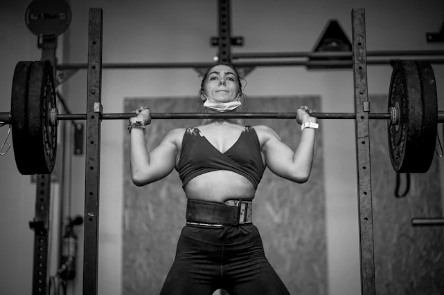A motivated person lifting weights in a bright, modern gym setting.