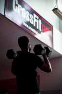 man in black t-shirt holding black dumbbell