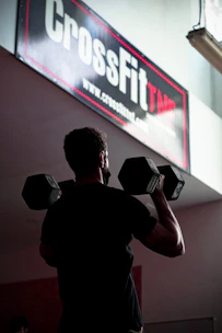 A dedicated trainer coaching a client through a CrossFit workout in a bright gym.