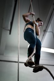 woman in blue denim jeans and brown boots climbing on brown rope