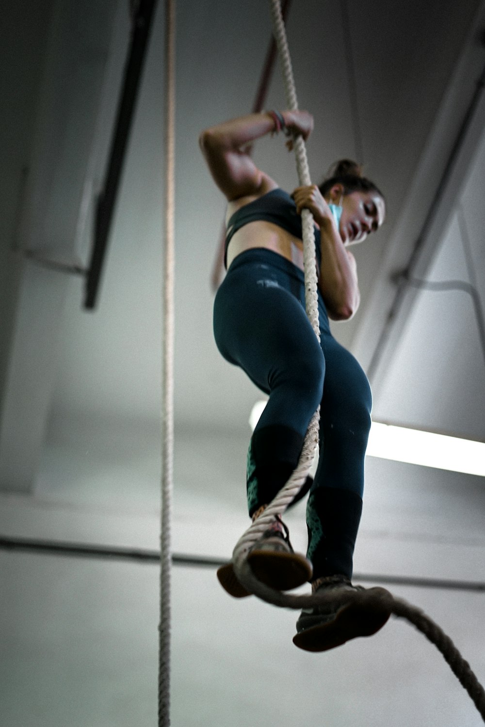 woman in blue denim jeans and brown boots climbing on brown rope