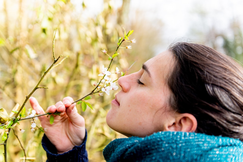 woman in blue knit sweater holding yellow flower during daytime