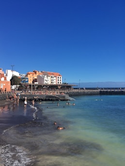 A vibrant beach scene showcasing travelers enjoying a sunlit shoreline with clear blue skies