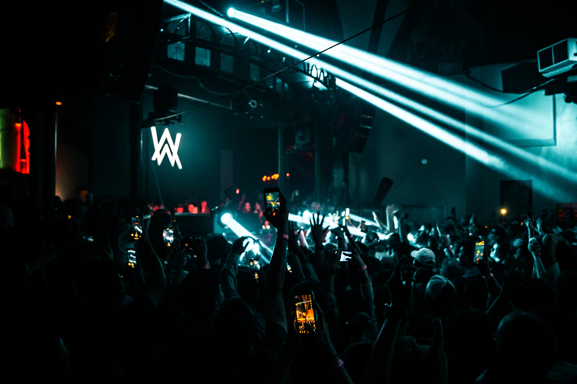 A dynamic shot of an energetic crowd dancing to beats at a night concert, hands in the air.