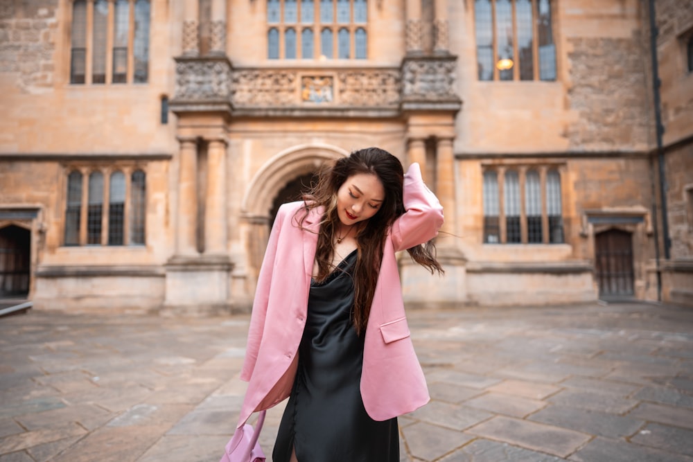 woman in pink coat standing on sidewalk during daytime