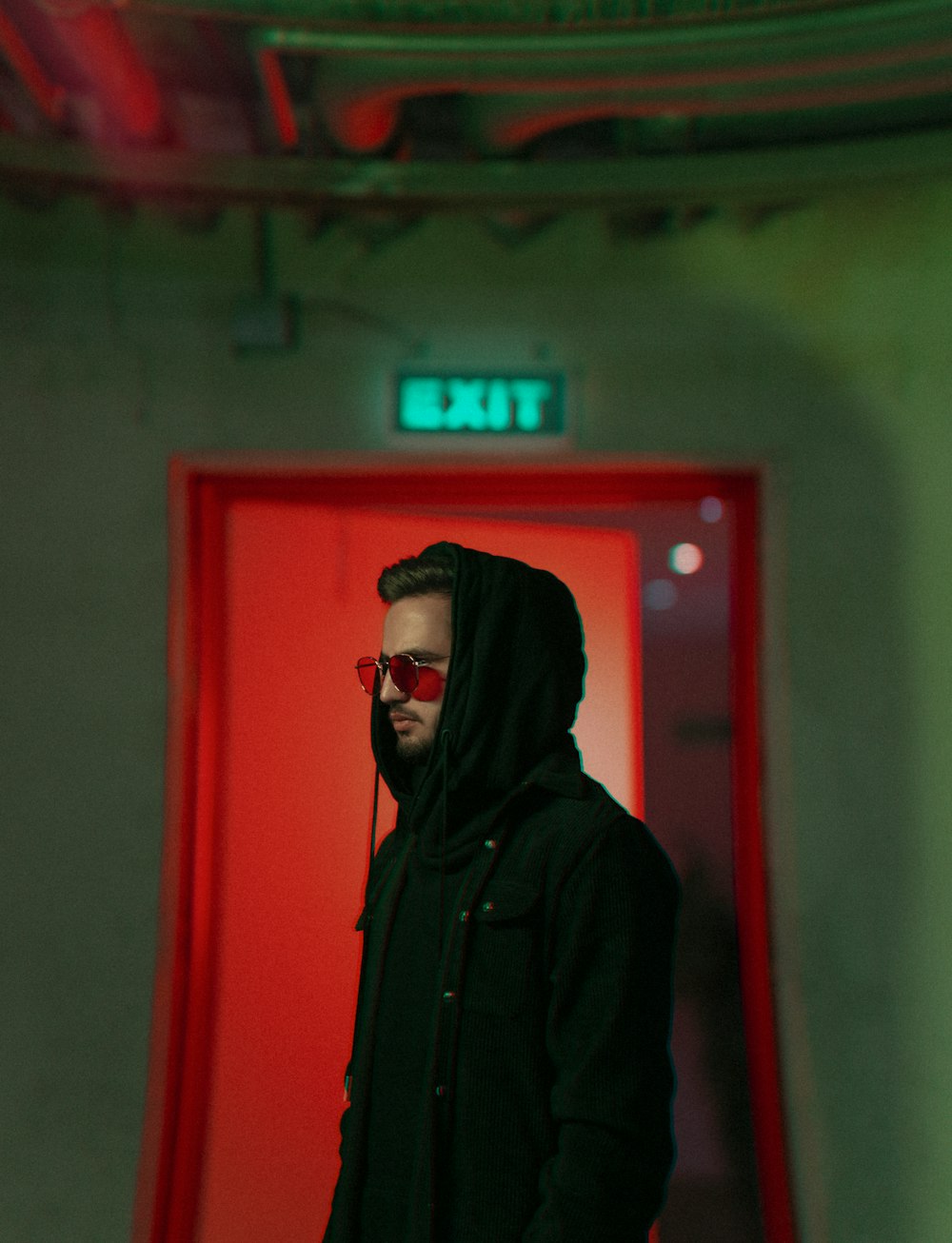 woman in black hoodie standing near red door