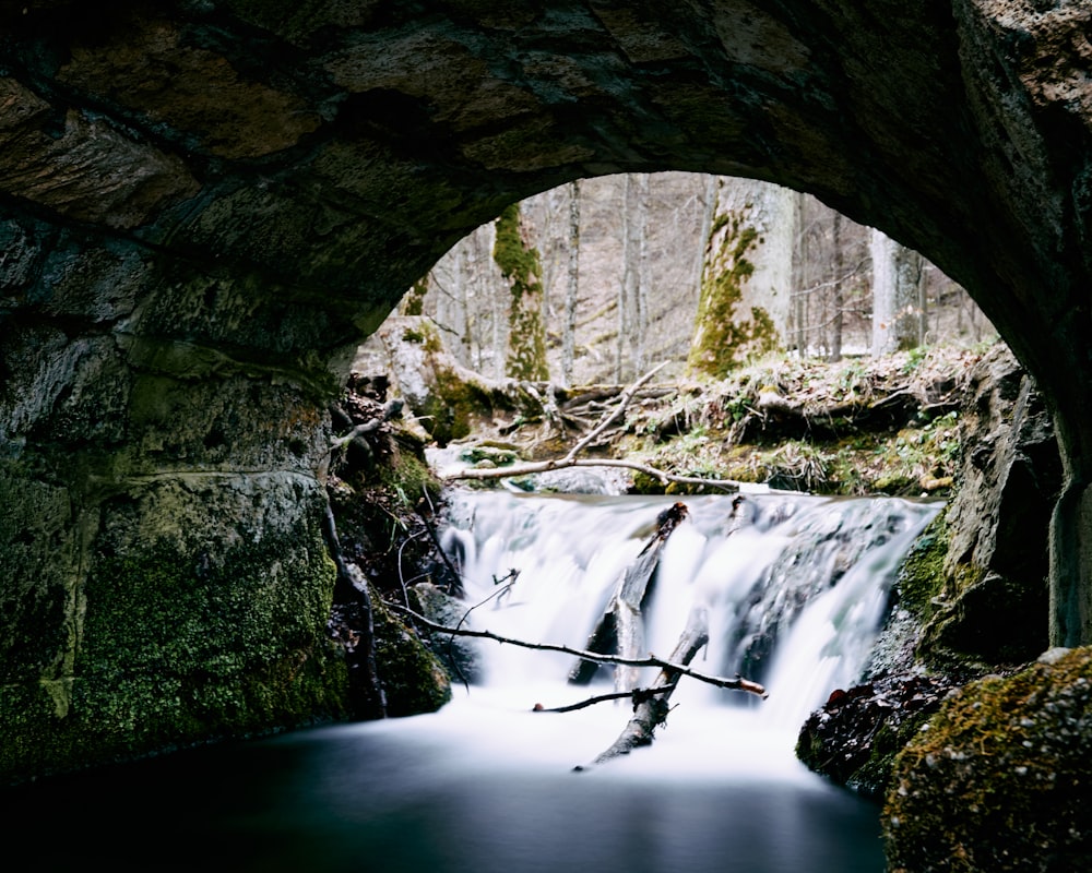 water falls under gray concrete arch bridge during daytime