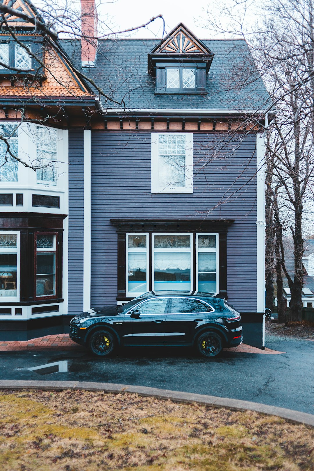 black coupe parked in front of white wooden house