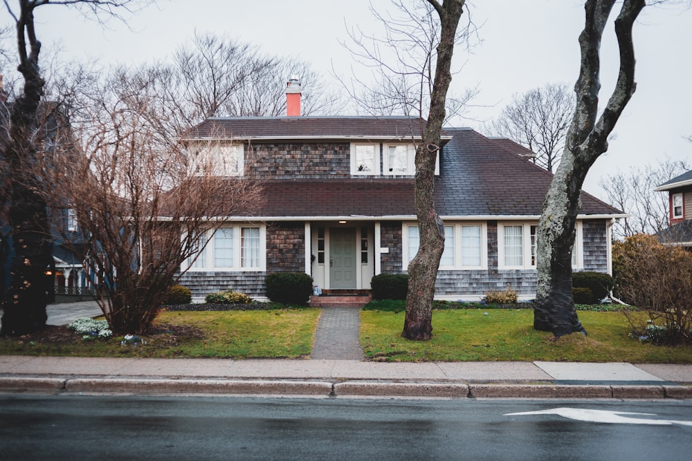 white and brown concrete house near bare trees during daytime