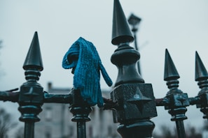 A close-up of a soft, knitted scarf in deep navy blue, draped over a rustic wooden bench dusted with snow.