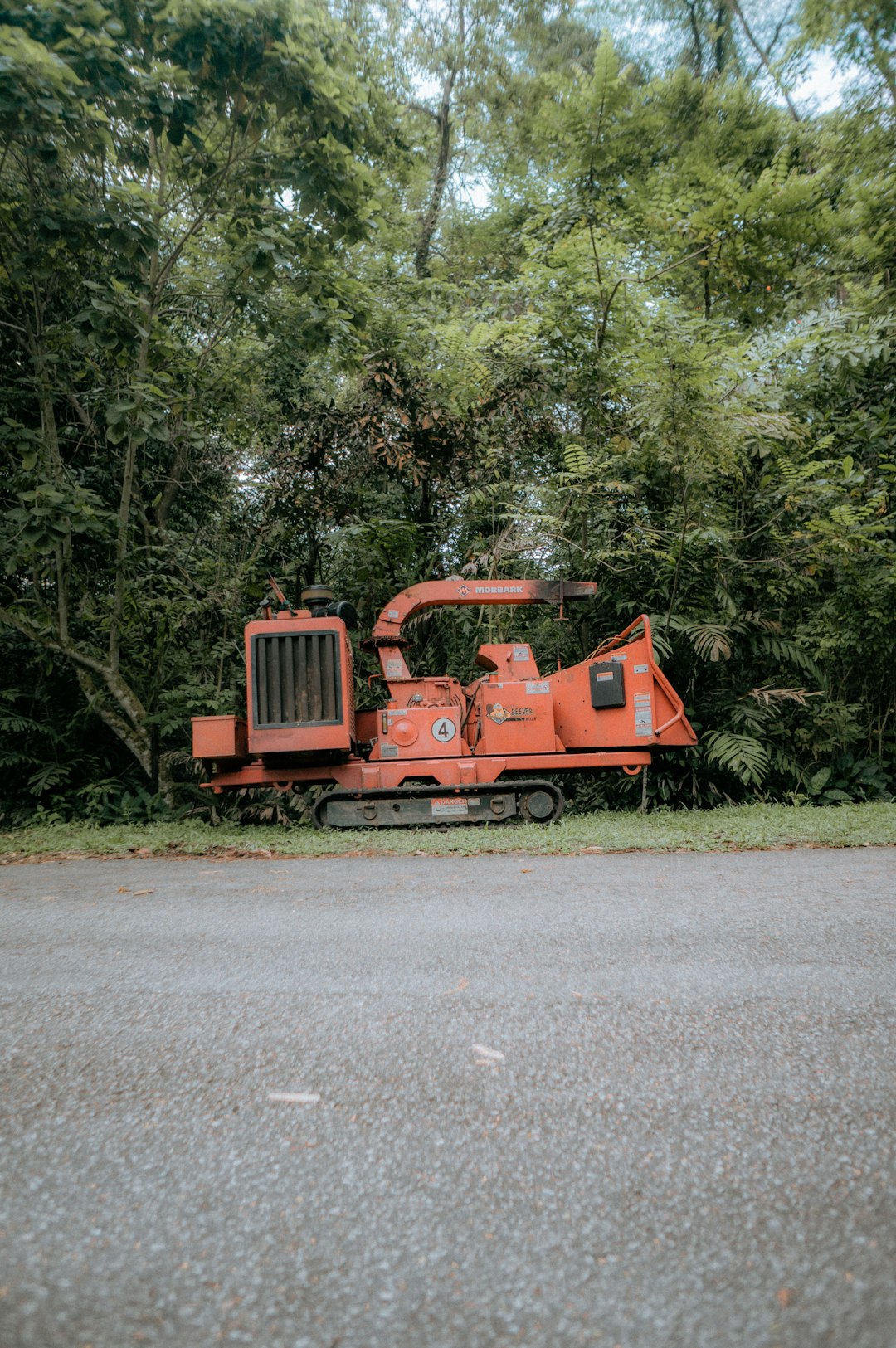 an orange tractor sitting on the side of a road