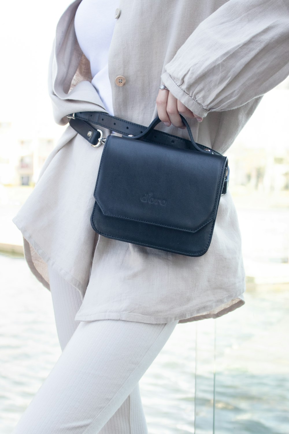 person in white coat carrying black leather sling bag