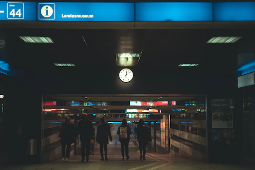 Night view of a high-visibility LED screen illuminating a crowded station entrance.