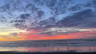 A vibrant sunset over Bacnotan beach with surfers carrying their boards along the shore.