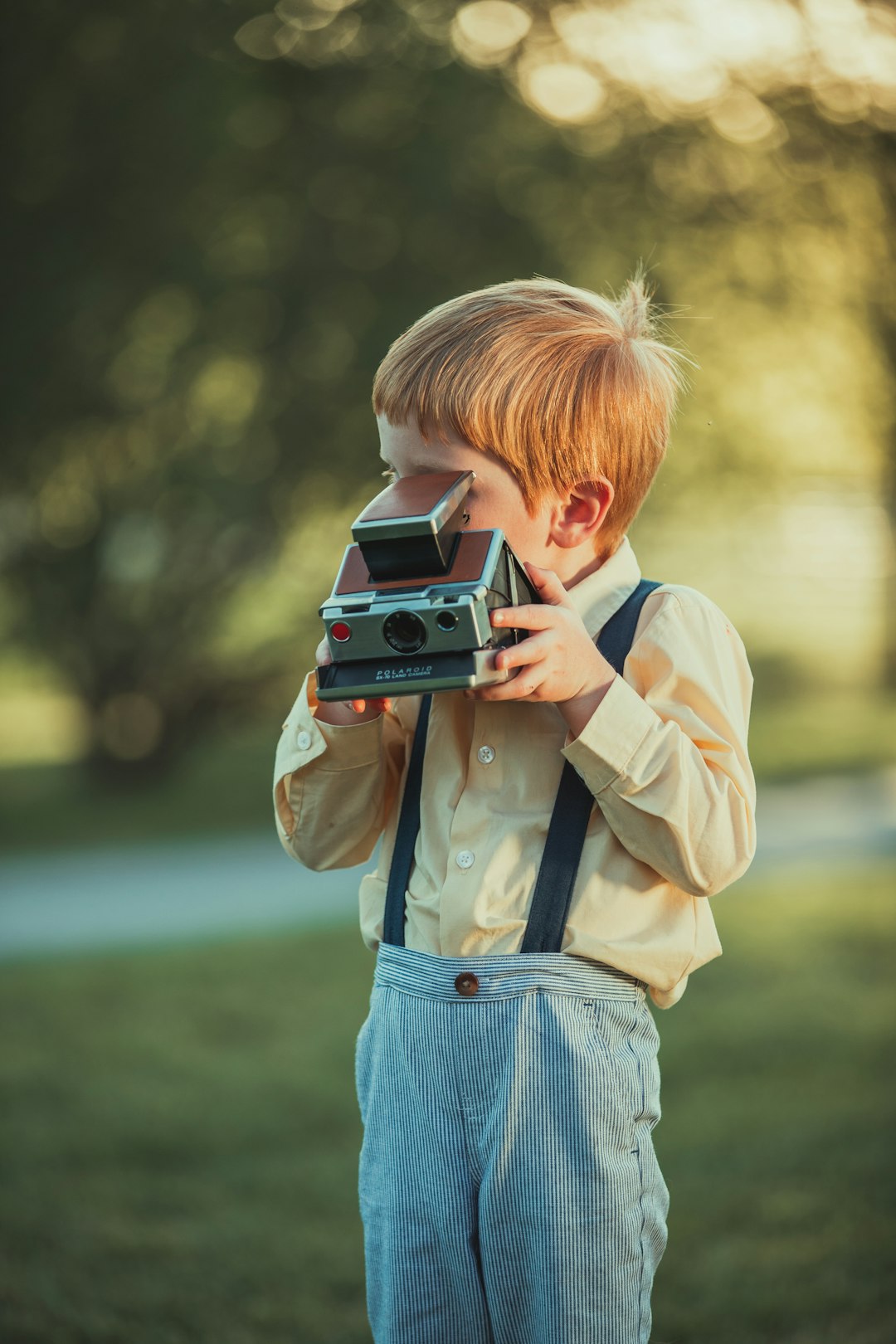 boy in beige jacket holding camera