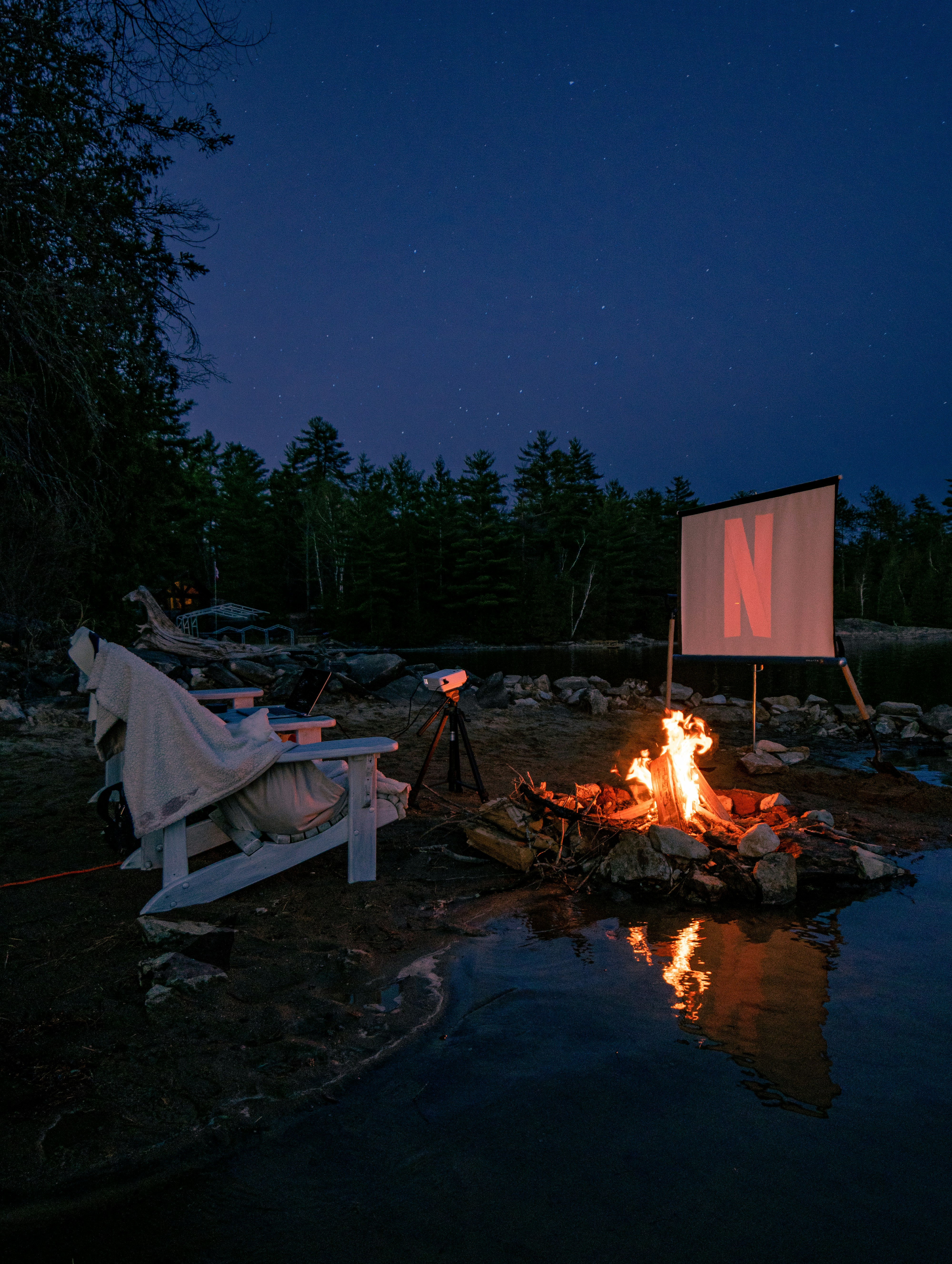 A cozy night under the stars on the beach of a lake watching a movie