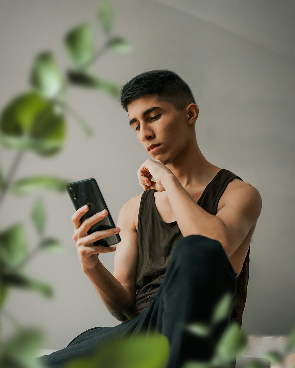 woman in black tank top holding black smartphone