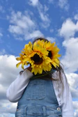 A child smiling widely while holding a freshly picked sunflower.
