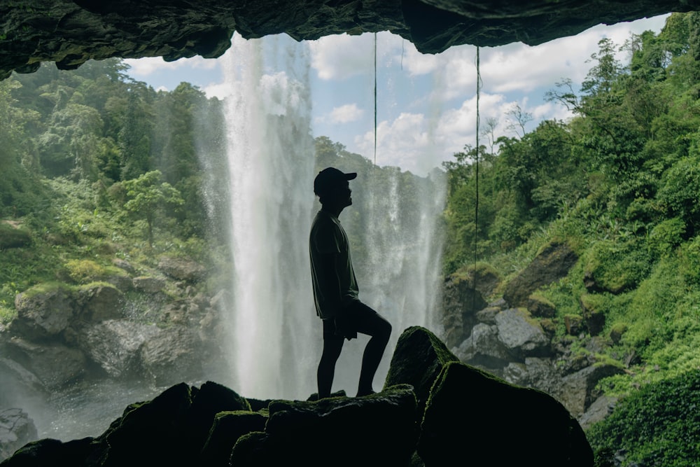 man standing on rock near waterfalls during daytime