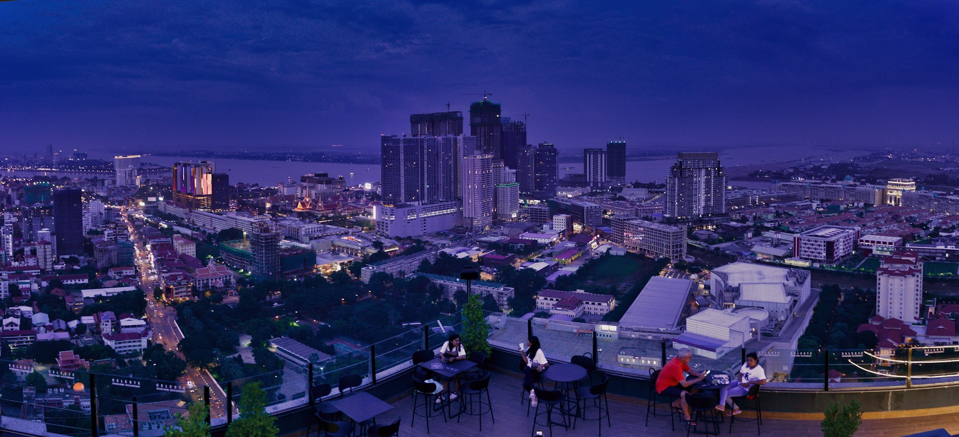 people sitting on chairs near table and high rise buildings during night time