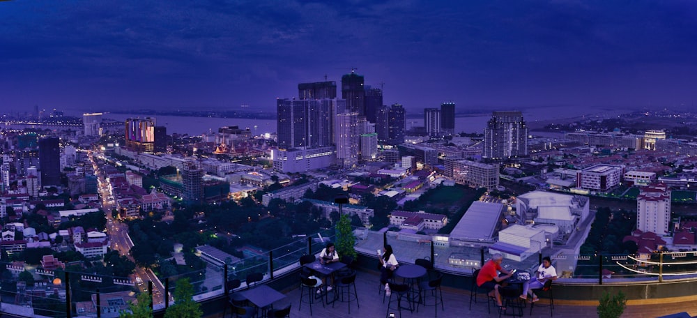 people sitting on chairs near table and high rise buildings during night time