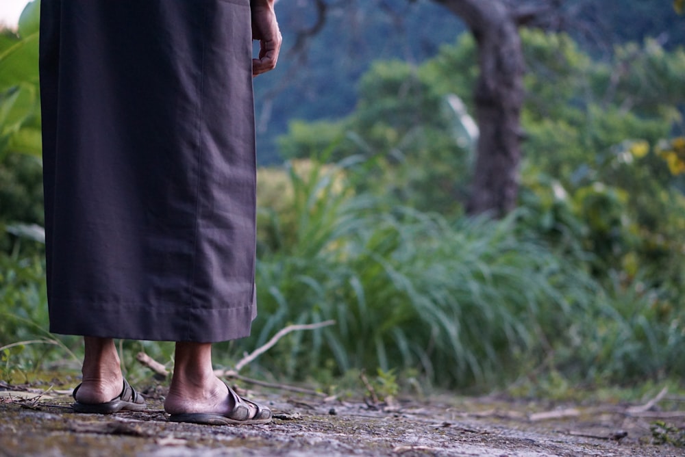 mulher na saia preta e sandálias pretas de pé no caminho de terra marrom