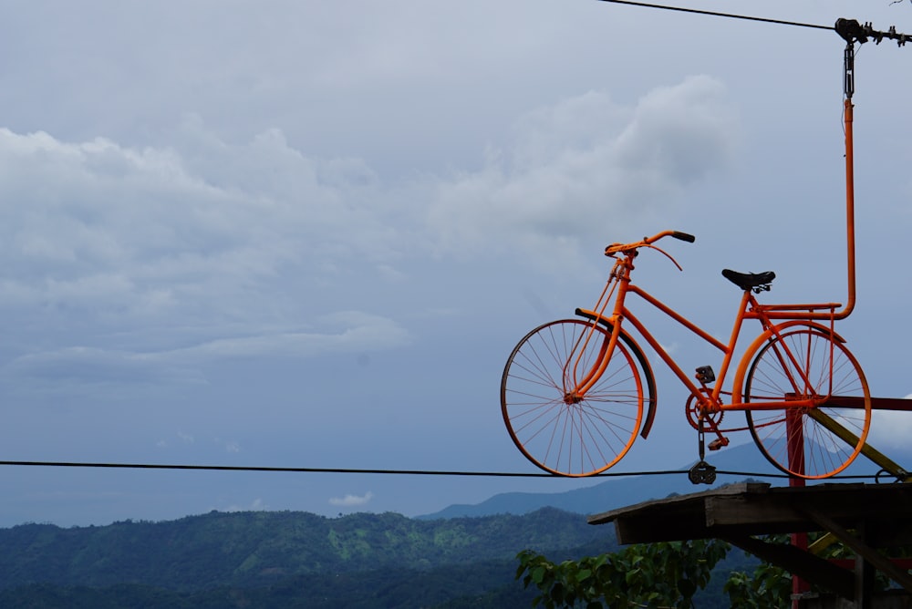 Vélo de ville rouge sur clôture en bois brun près du plan d’eau pendant la journée