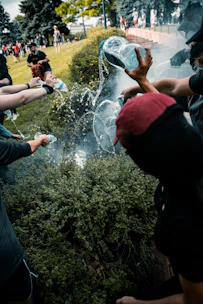 Volunteers wearing masks distributing bottled water on an urban street with subtle smoke and dramatic lighting.