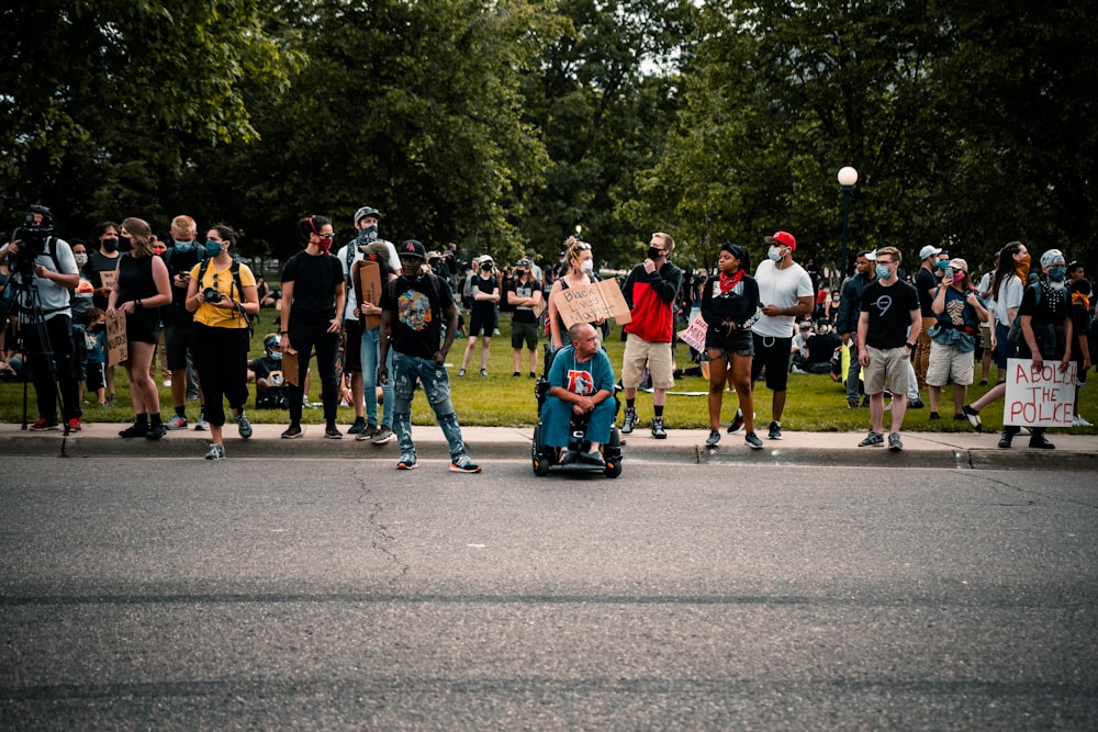 personnes debout sur une route asphaltée grise pendant la journée