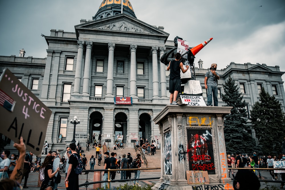 Personas de pie frente a un edificio de hormigón gris durante el día