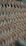A close-up view of a woven material with a crisscross pattern made from thin, slightly curved strips of wood. The image captures the intricate details and texture of the weave with a shallow depth of field, blurring the background.