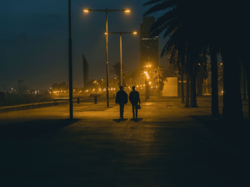 man and woman walking on sidewalk during night time