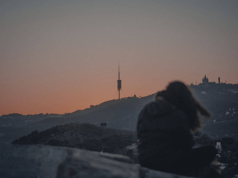 silhouette of person sitting on rock during sunset