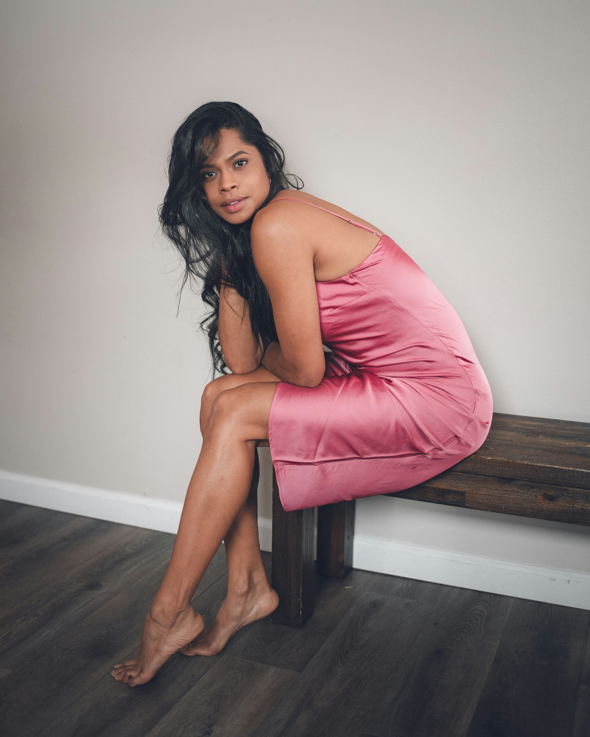 woman in pink sleeveless dress sitting on brown wooden bench