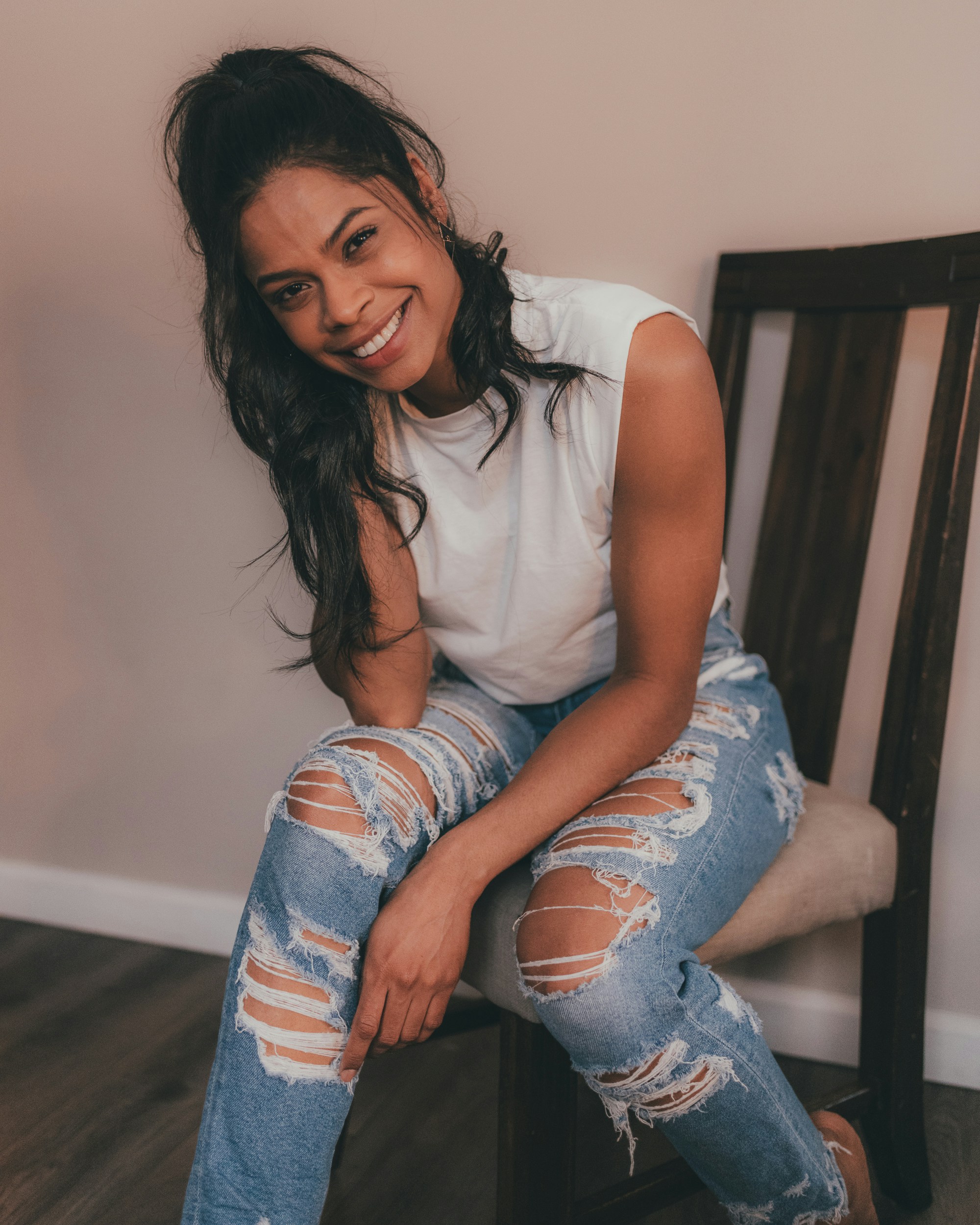 woman in white tank top and blue denim jeans sitting on chair