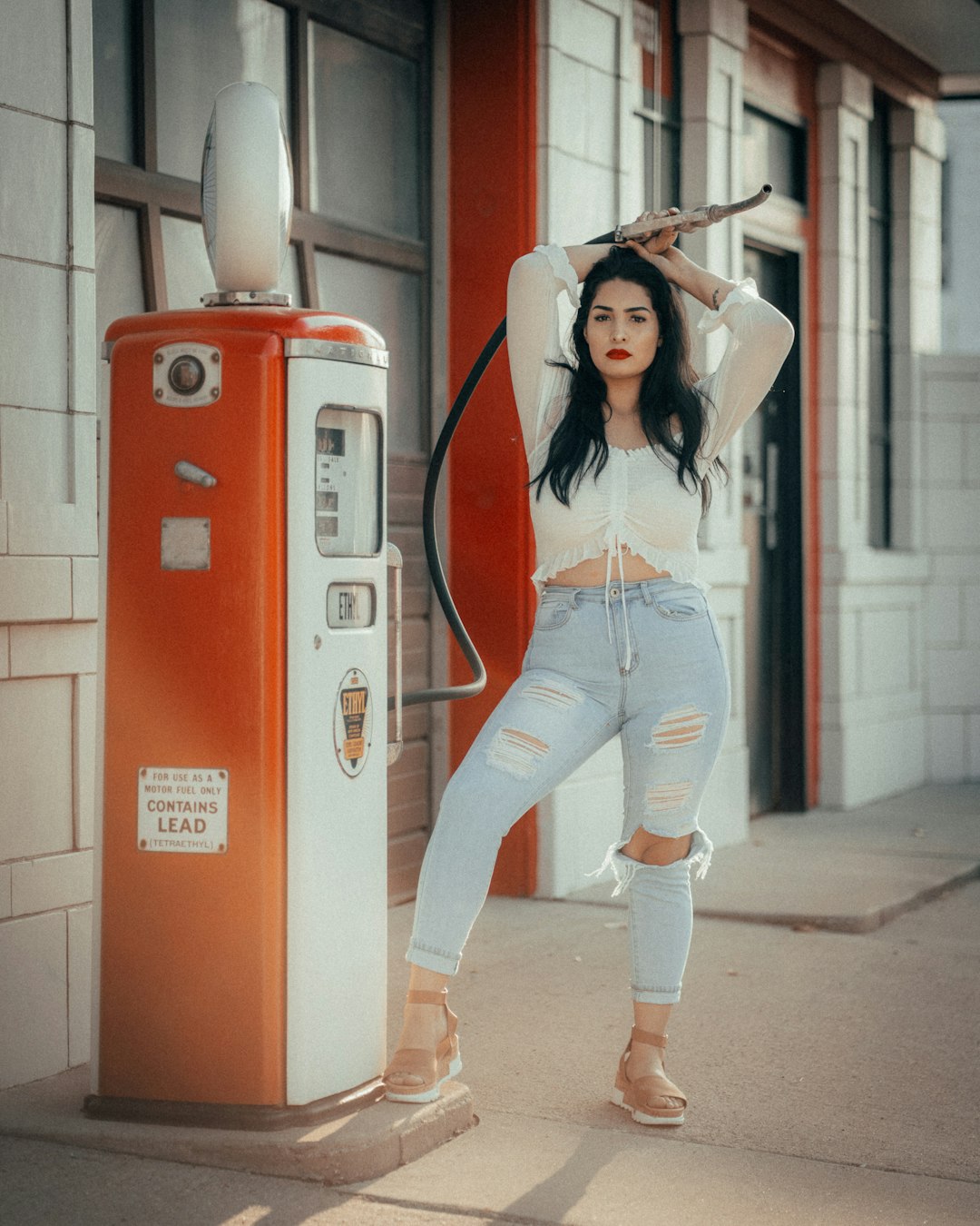 woman in red tank top and blue denim jeans standing beside red and white water dispenser