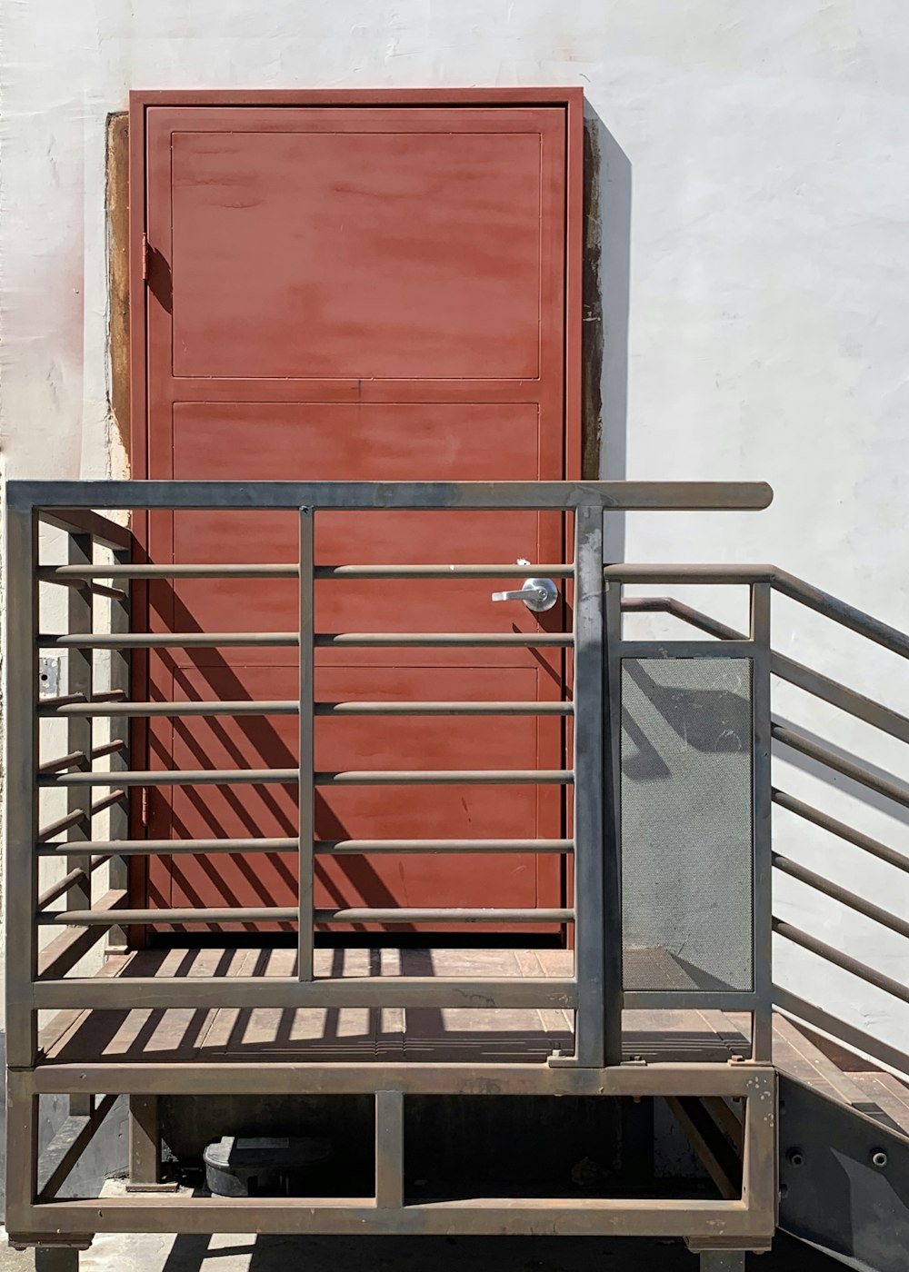black metal railings near red wooden door