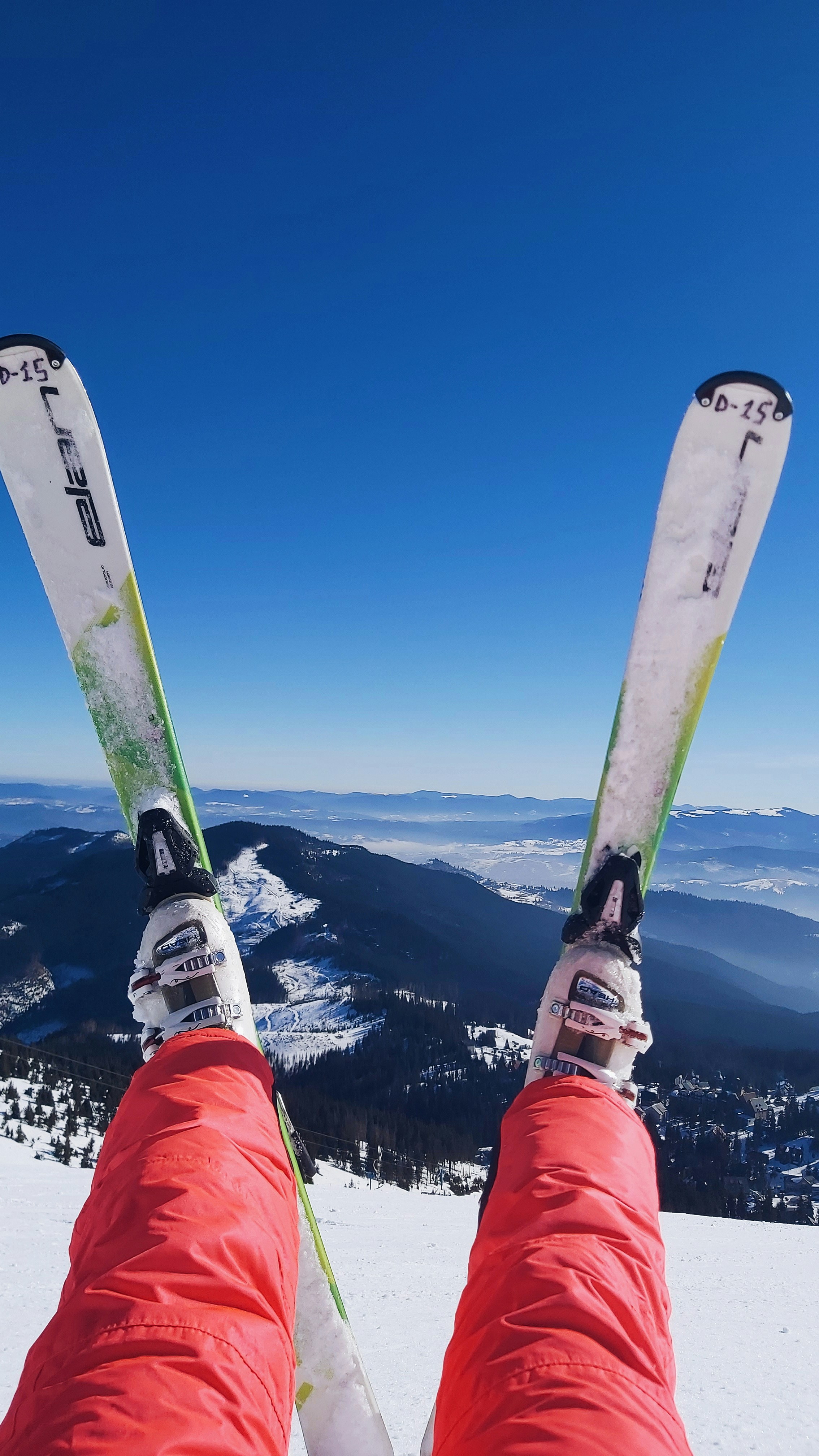 赤と白のスノーゴーグルと赤のジャケットを着た人が青と白のスノーボードを持っている