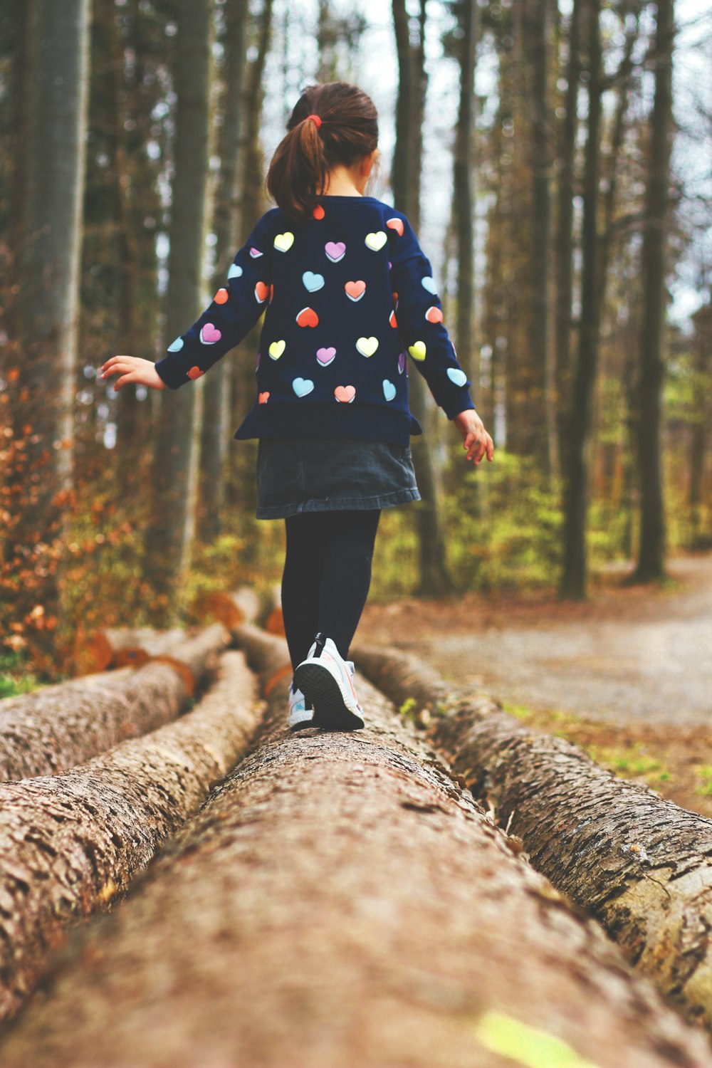 child in blue and orange striped sweater and black pants walking on dirt road during daytime