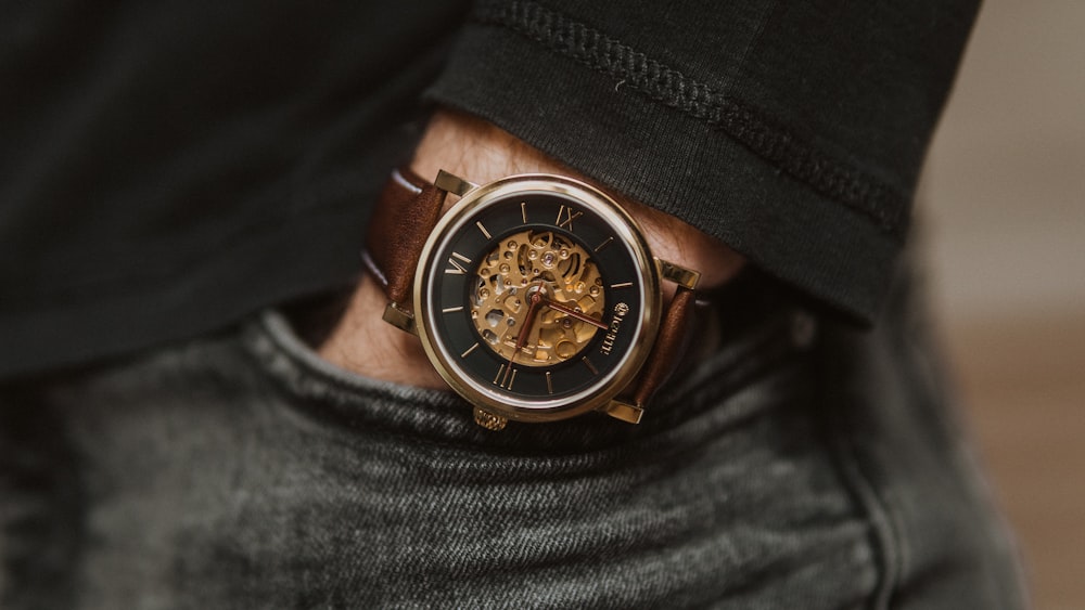 person wearing black leather strap gold and black chronograph watch