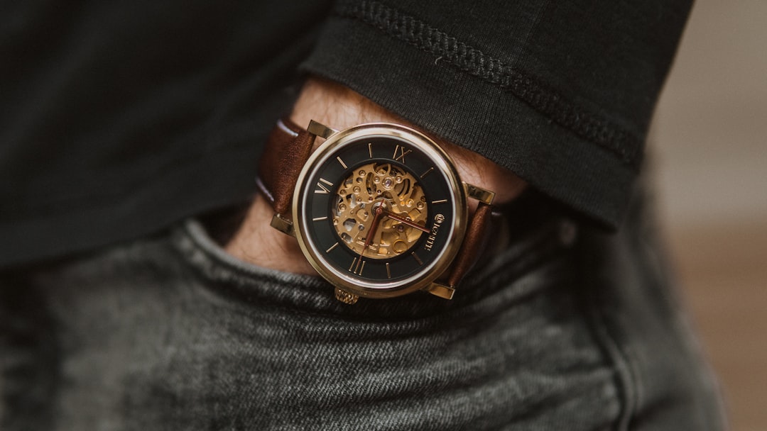 person wearing black leather strap gold and black chronograph watch,