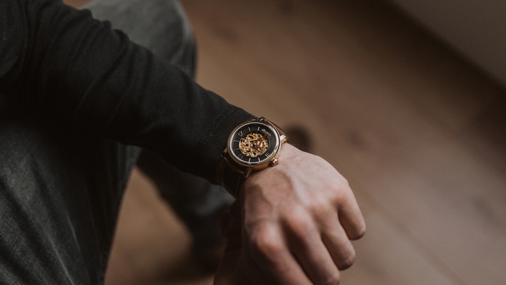 person wearing gold and black analog watch