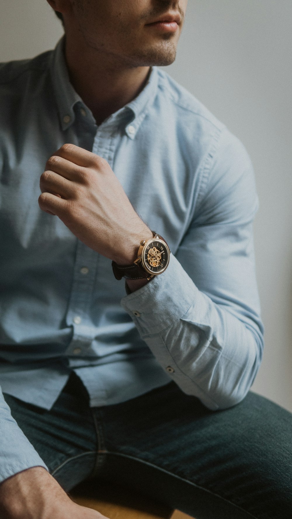 man in blue dress shirt wearing gold round analog watch