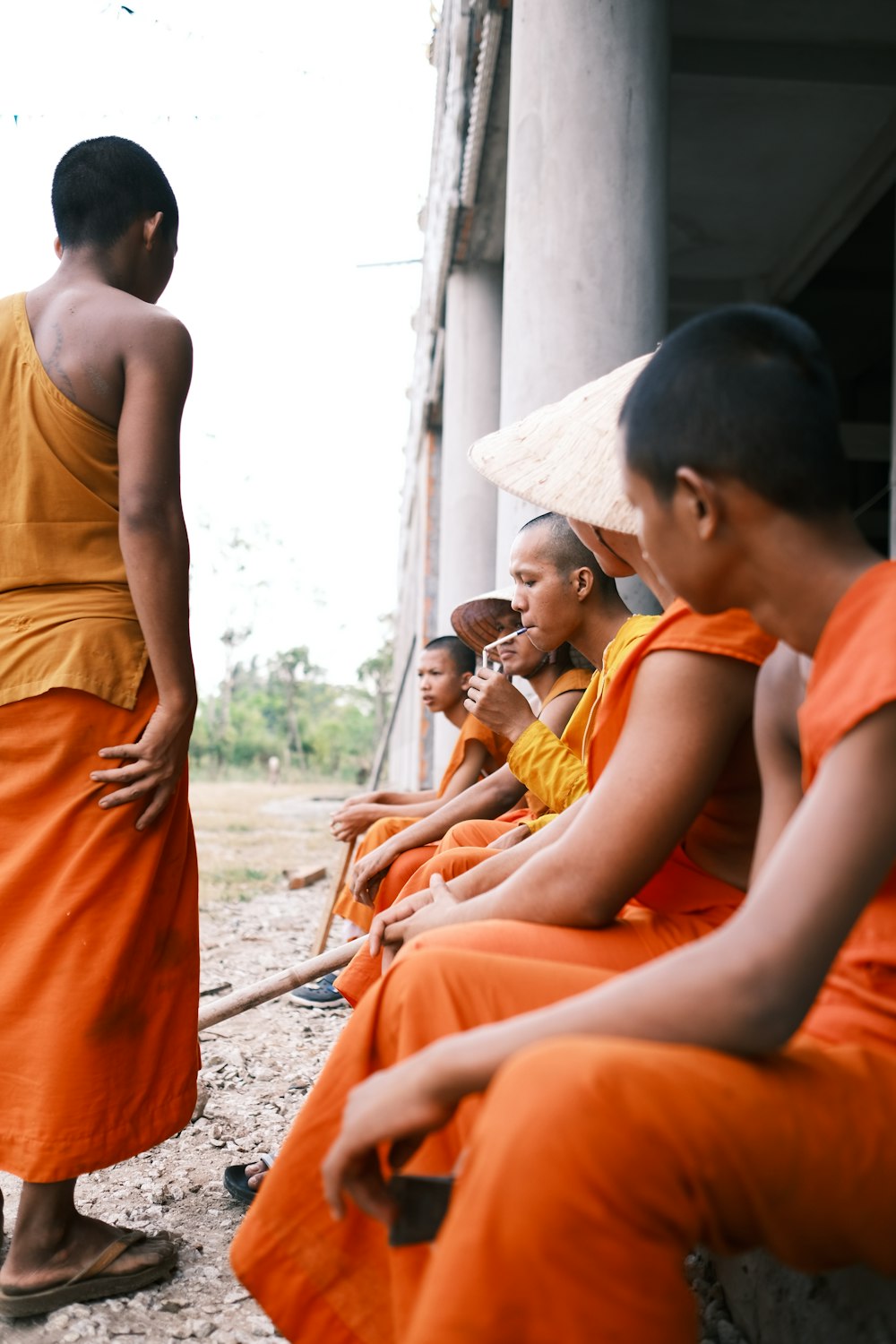 2 boys in orange tank top sitting on ground during daytime