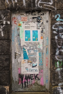 A weathered trailer door adorned with quirky signs and faded paint.